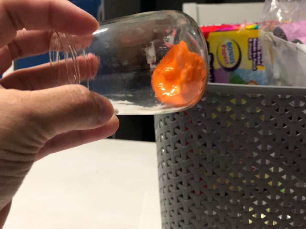 Clear jar tilted on side with paint inside moving around to coat inside of jar