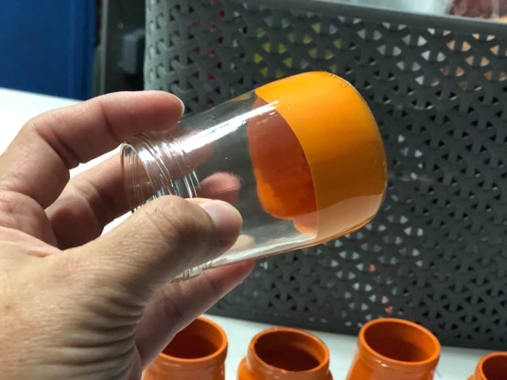Clear jar tilted on side with paint inside moving around to coat inside of jar