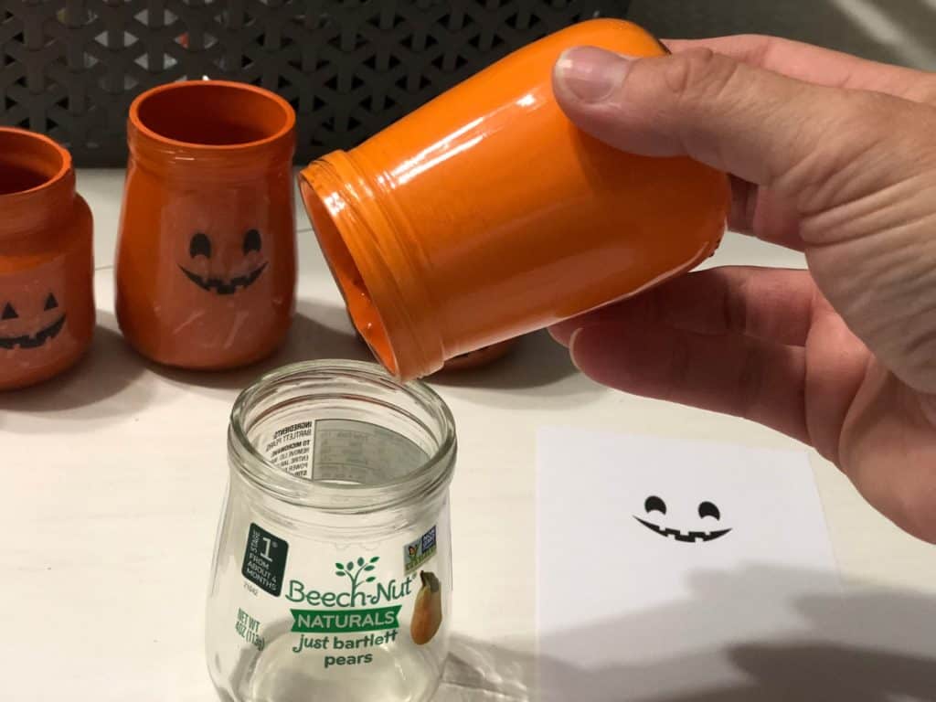 Paint pouring from an orange painted jar to a leftover clear unused jar