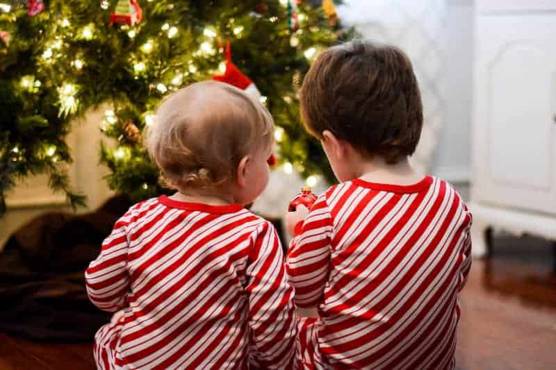 2 small boys in front of Christmas tree in candy cane pajamas