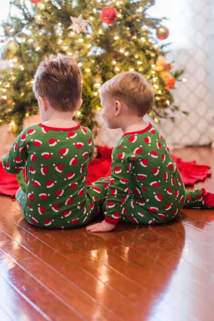 2 little boys in front of Christmas Tree in Santa Hat Pajamas