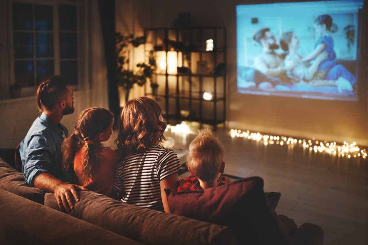 Family sitting together on a couch with low lights on watching a movie