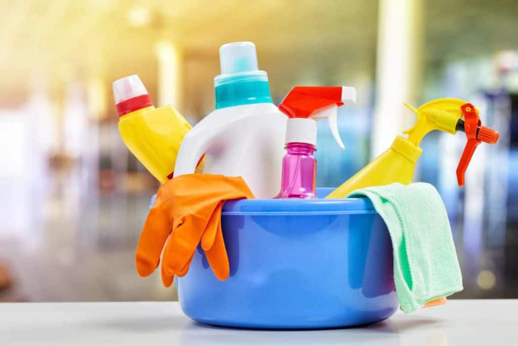 Bucket of cleaning supplies with cleaners, gloves and cloth