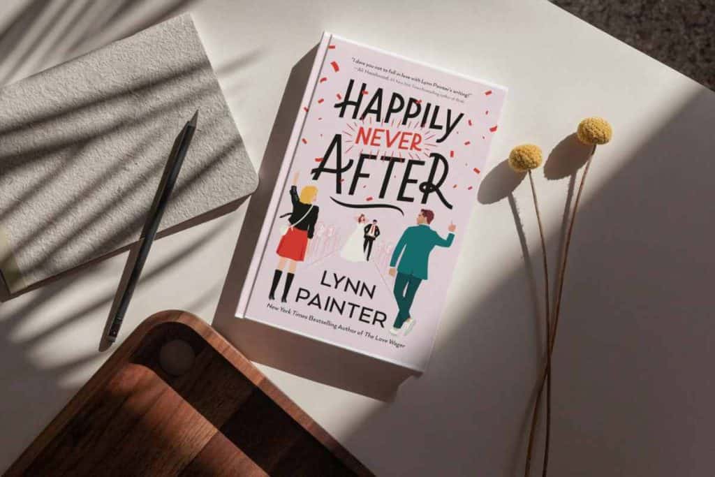 Book titled "Happily Never After" sitting on a table with a paper and pen and wooden tray and a flower