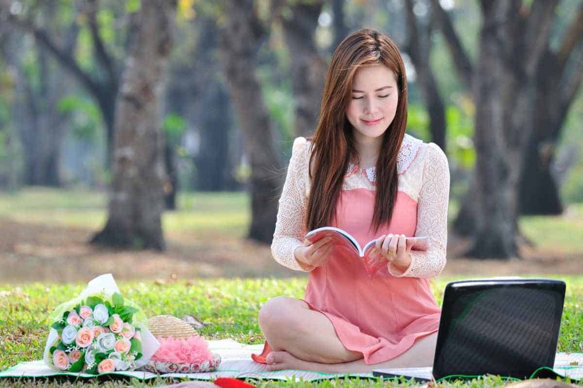 Woman reading outside in a park on a blanket in Spring