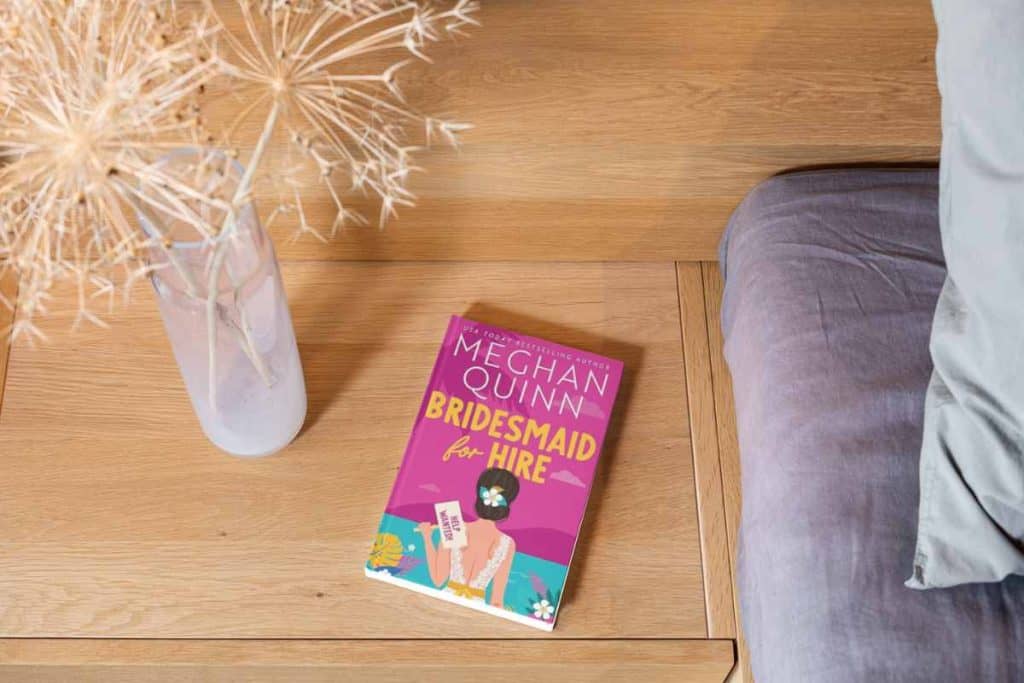 Book titled "Bridesmaid for Hire" on a nightstand next to a bed