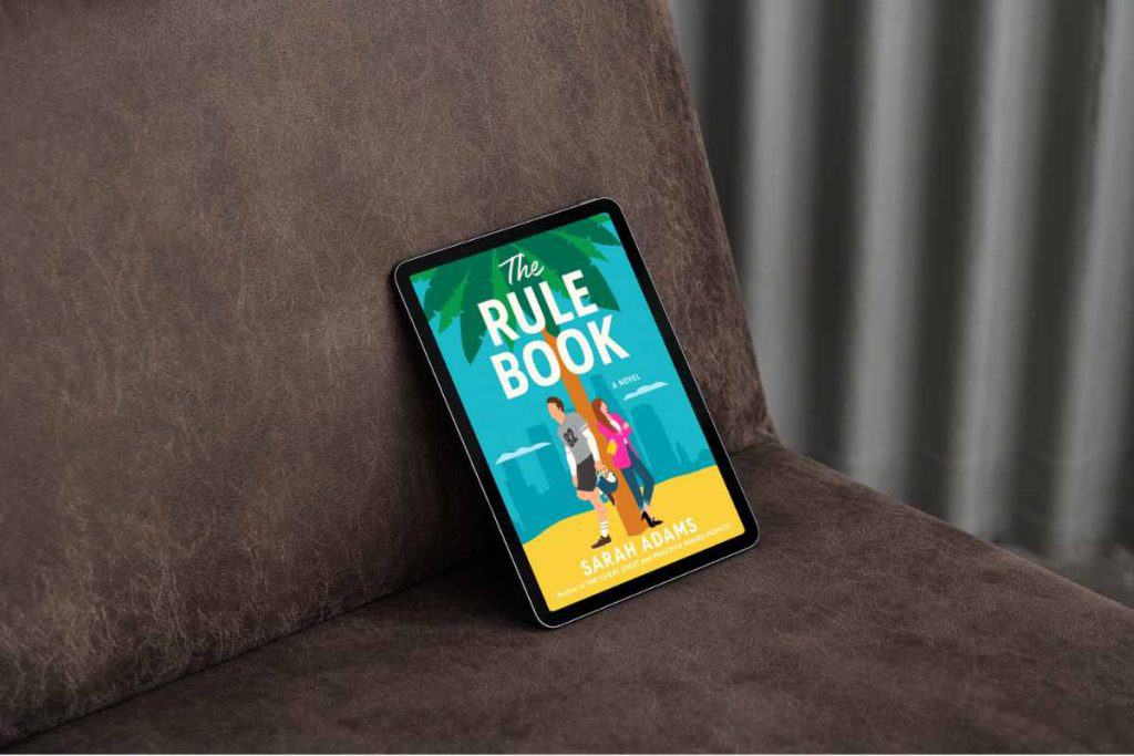 An e-reader in a chair propped up with the book titled "The Rule BooK" pulled up on the screen