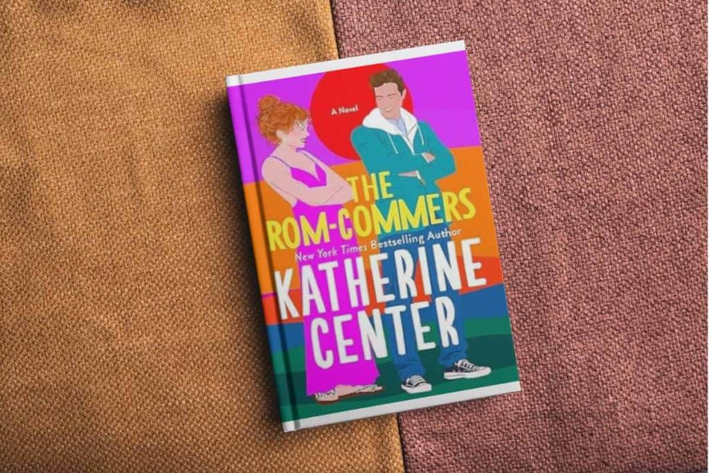 Book titled "The Rom-Commers" sitting on a couch cushion