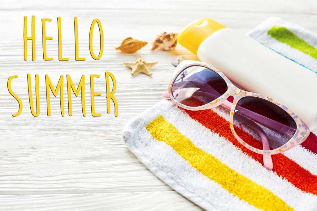 "Hello Summer" graphic with a beach towel, sea shells, sun tan lotion and sunglasses