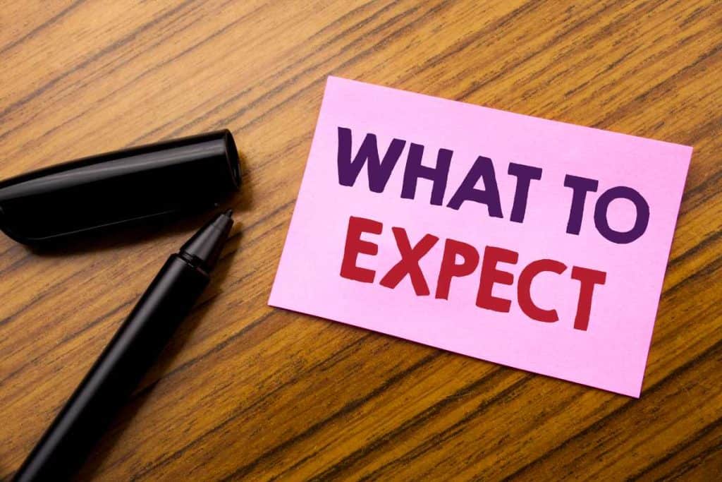 A pink piece of paper on a desk that says "What to Expect" and a black pen next to it.