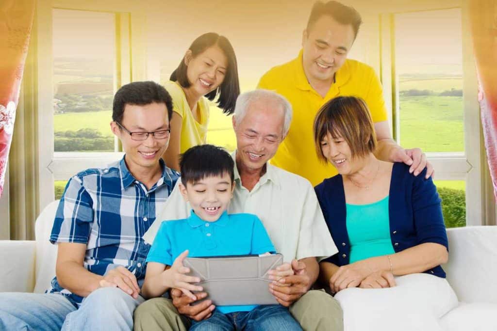 A family gathered around a child holding an ipad with everyone smiling