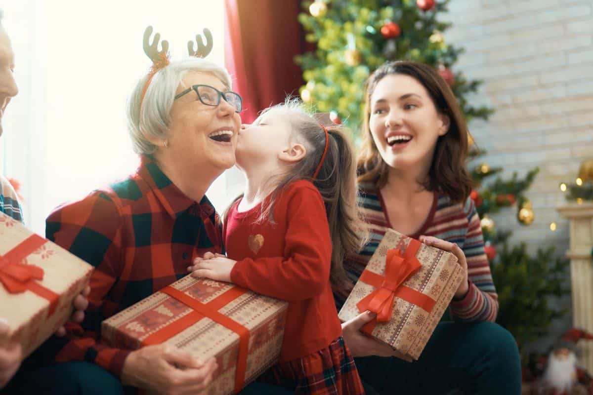 Little girl giving Grandma a Christmas present and a kiss.