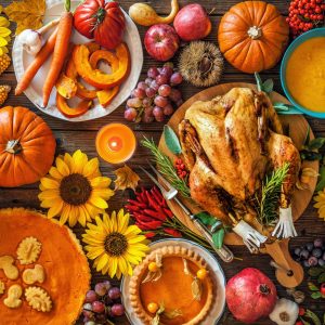 A beautiful thanksgiving table filled with all the usual Thanksgiving foods like squash, turkey, pumpkin pie and gravy.