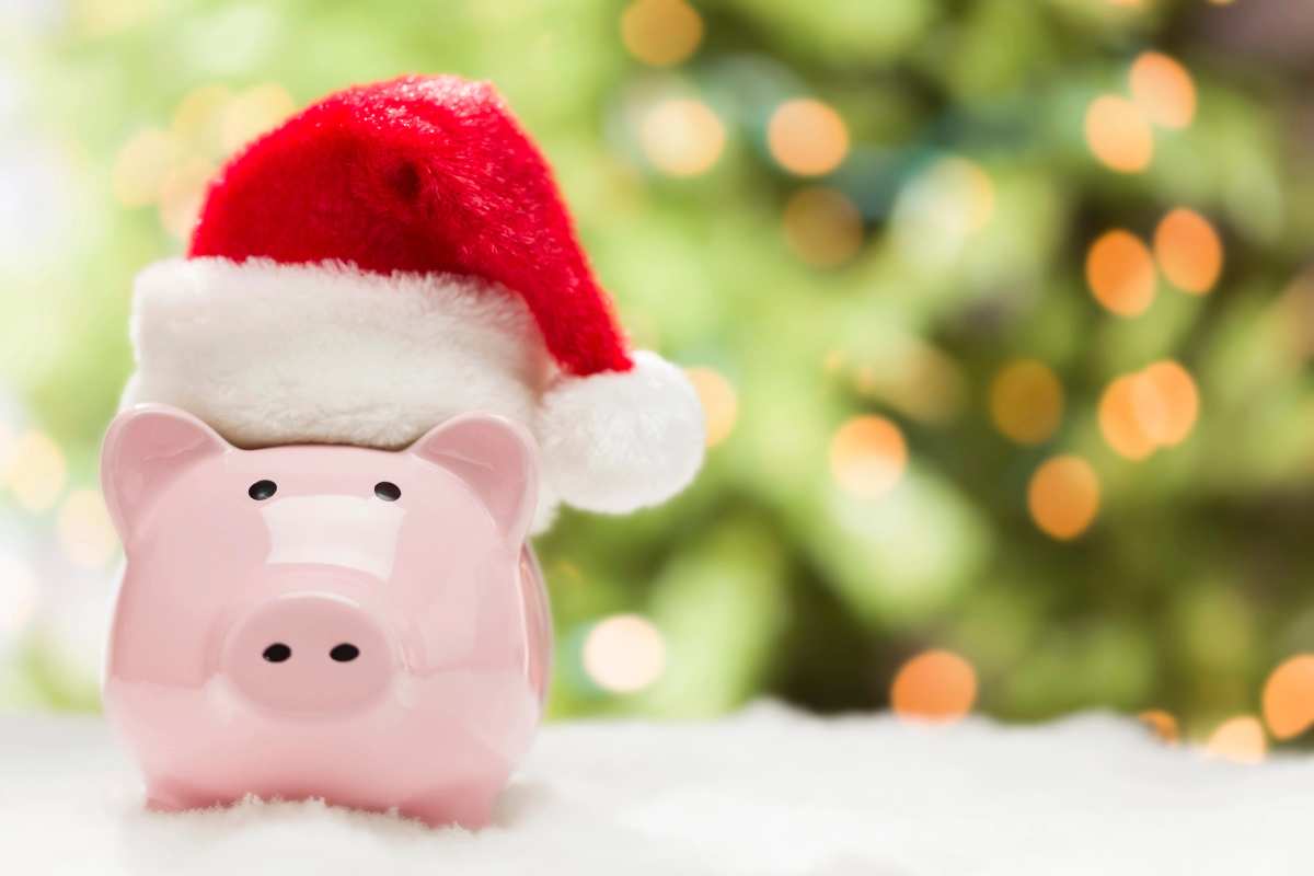 Piggy bank sitting in fake snow with a Santa hat on