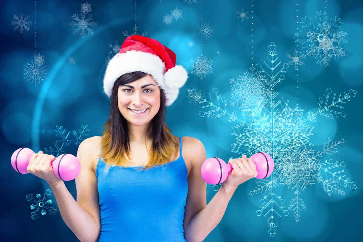 A woman with a santa hat on lifting dumbells