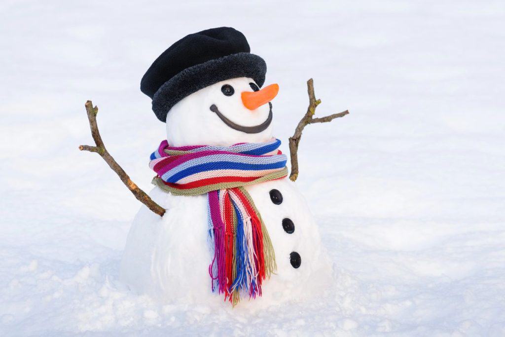 Snowman with a black hat and a striped scarf in a field of snow.