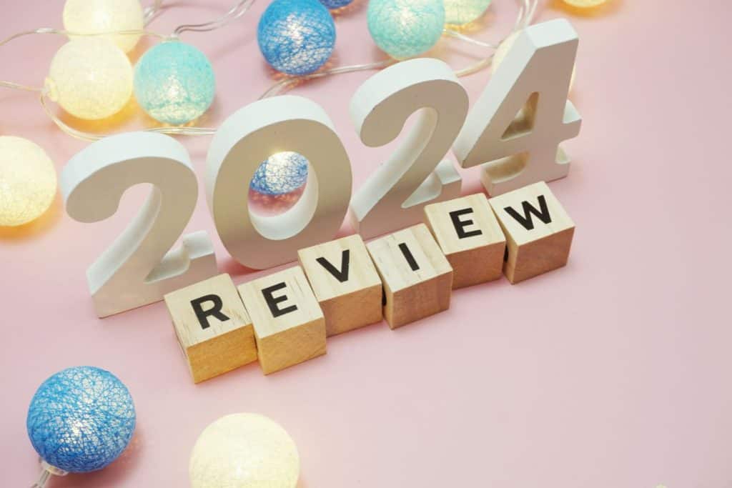 Big block letters and numbers on a pink background with lights that says "2024 Review"